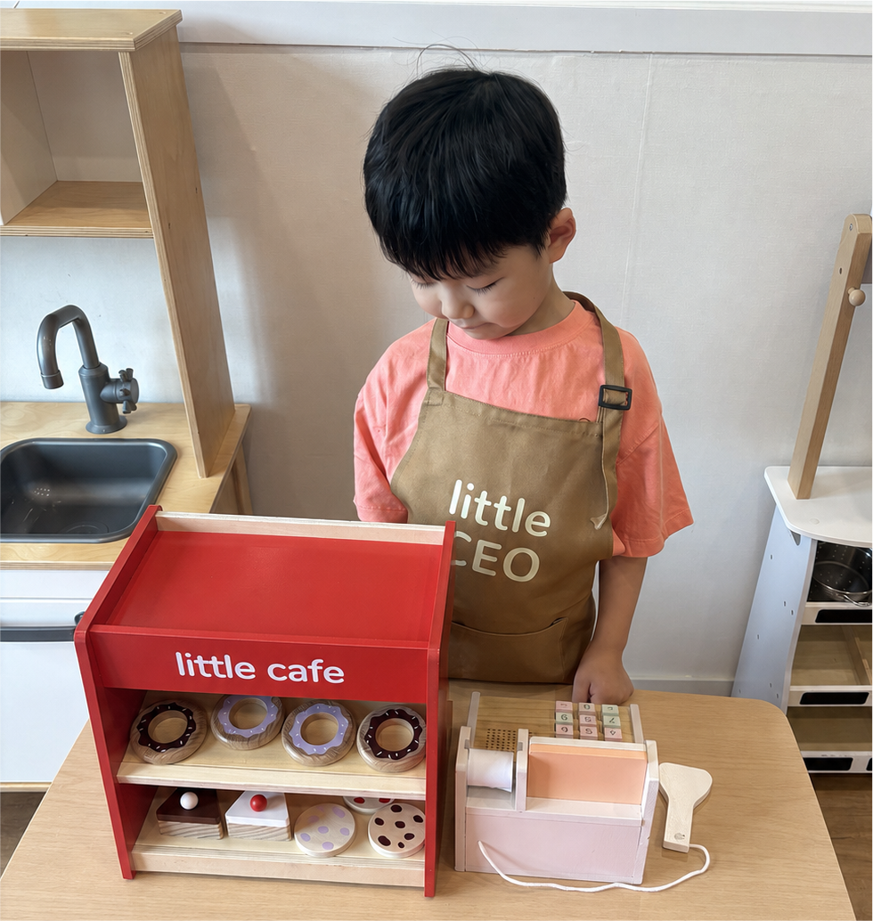 앞치마를 입고 카페 사장님 역할놀이를 하는 아이